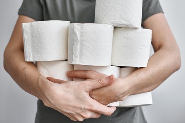 A man with his arms full of toilet paper