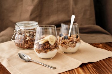 Close up of delicious layered dessert in glass jar, Homemade yogurt with granola and berries, Granola baked with nuts and honey