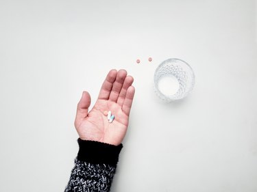 Hand holding lipozene amorphophallus konjac maximum strength pills next to glass of water on white background