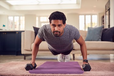 Person exercising with dumbbells in their living room as part of a 5-minute dumbbell workout you can do every day.
