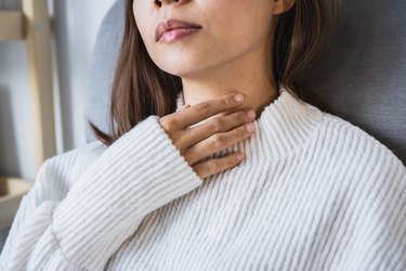 woman with her hand on her throat because she has globus sensation
