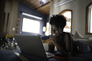 a person watching a movie on a laptop at home with sun coming in the window behind them