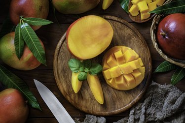 Sliced mangoes in a wooden plate on a table in rustic kitchen