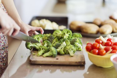 Woman chopping broccoli in kitchen