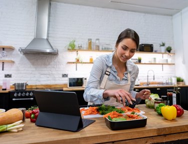 Woman cooking dinner following an online recipe on her meal prep app