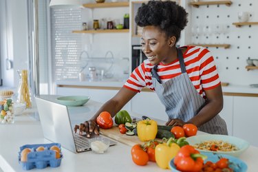 Young African-American woman cooking at home and looking for recipes online