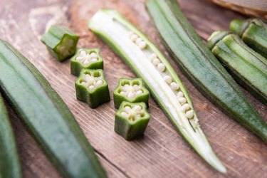 Close view of fresh, raw okra slices on a wooden table, to represent an okra allergy