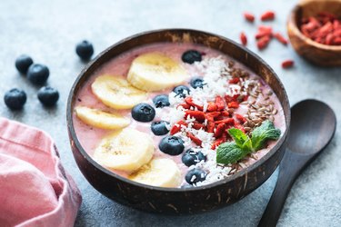 an overhead photo of a healthy acai bowl topped banana, blueberries, and other fruits and seeds as an example of a blue zones-inspired breakfast for healthy aging