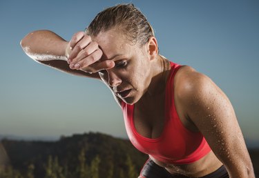 person wiping sweat from forehead after body temperature increased during exercise