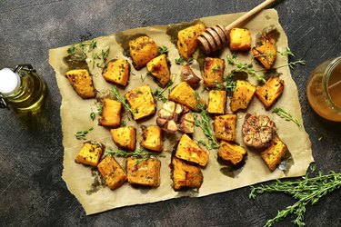 Oven baked banana squash slices on parchment paper with honey