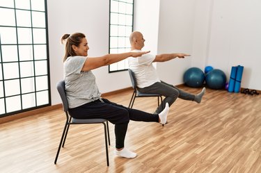 older couple doing a seated core workout on chairs