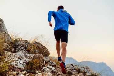 跑回男运动员跑步上山的小道在石头