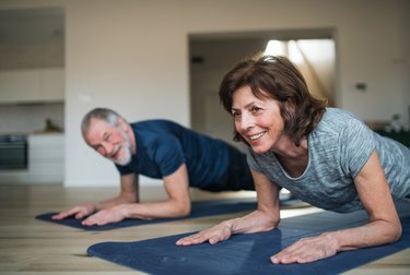 closeup of a senior woman and man doing a forearm plank at home