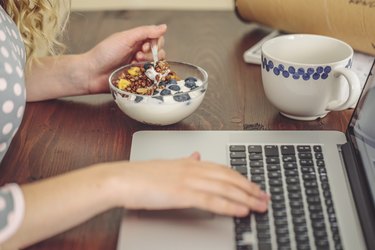 Young woman at home working and eating a bowl of yogurt, as a remedy for yeast infection