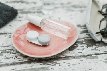 contact lens case and eyeglasses on a bathroom surface