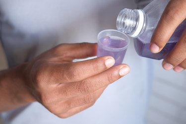 close view of a person measuring mouthwash in a small cup