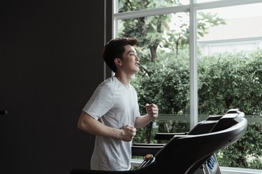 man power walking on treadmill at home next to window