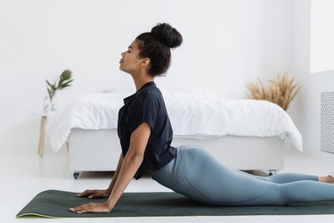Black woman doing upward-facing dog pose, as a way to combat age-related posture changes