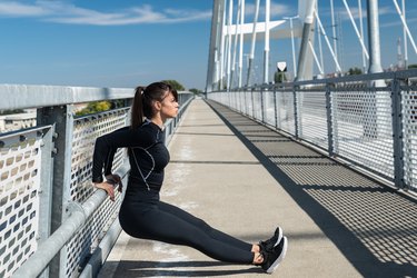 caucasian woman wearing black doing triceps dips on a bridge railing outside