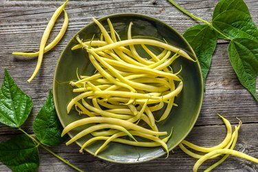 Fresh yellow wax beans on green plate