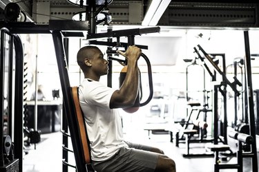 Person in gym using chest fly machine as an example of best gym exercises for losing arm fat.