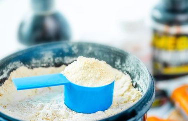Closeup blue measuring cup in protein powder