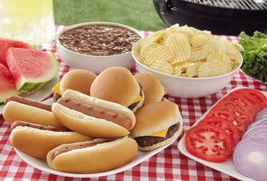 Gluten free buns with hot dogs and hamburgers on summer picnic table
