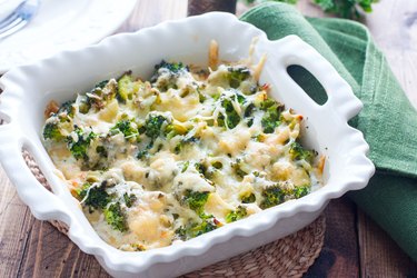 Baked broccoli with chicken and cheese recipe in a ceramic form on a wooden table, selective focus