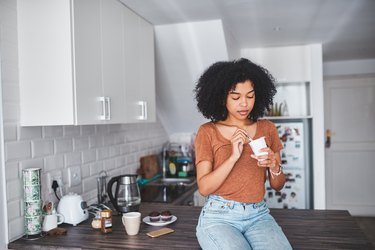 woman sitting on kitchen counter eating yogurt to prevent BV infection