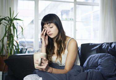 woman drinking coffee and looking tired because of silent reflux at night disrupting her sleep