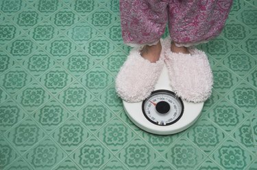 Close up of feet in slippers on bathroom scale