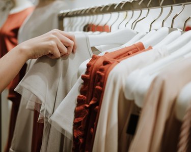 Close up of hand reaching for white shirt on clothing rack to show whether size 16-18 is fat and jeans weight length