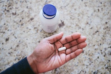 Woman Holds magnesium Pill in Palm of Hand