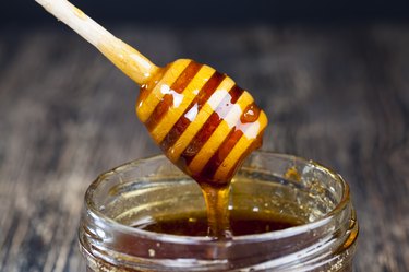 Honey dipper drizzling honey into a jar as a natural fat lip remedy