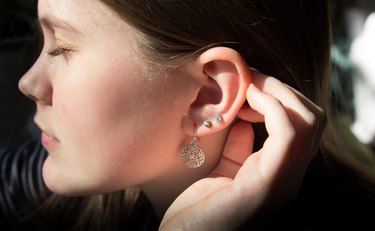 Close up profile view of a teenage girl pushing her hair behind her hear