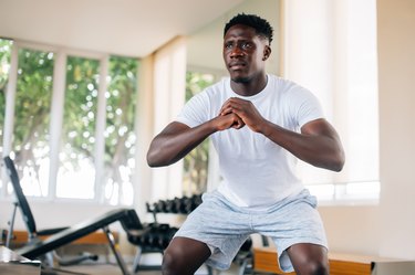 Person performing a squat at a gym to demonstrate how to make an exercise harder without buying heavier dumbbells.