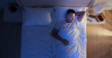 top view of a man sleeping in bed and having vivid dreams