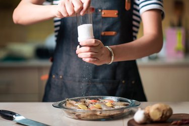 女人盐在玻璃碗新鲜的虾烹饪