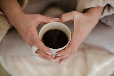 Top view of hands holding a mug of black coffee