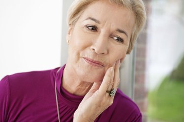 Close-up of an older person holding their left cheek