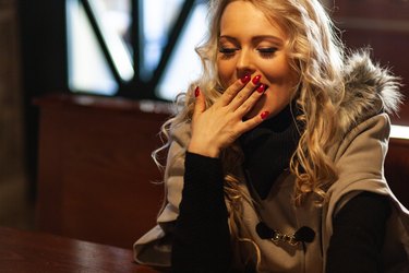 Polite young woman with her hand to her mouth