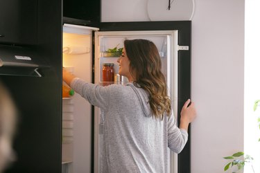 快乐的女人从冰箱里拿食物