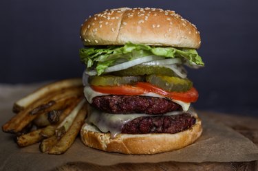 Double Venison Cheeseburger on a Wooden Cutting Board With French Fries