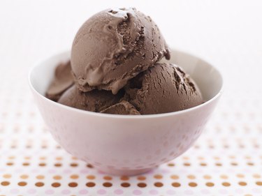 pink bowl of three scoops of chocolate ice cream on polkadot tablecloth