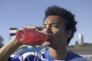 A soccer player drinking red Gatorade to quench his thirst