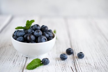 Freshly picked blueberries in bowl on wooden background. Concept for healthy eating and nutrition