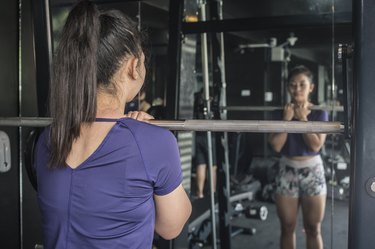 A person prepares to do a front squat on a smith machine at the gym