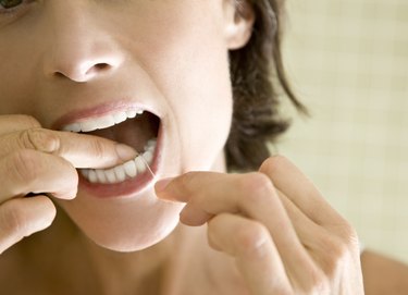 A woman in her 40s flossing her teeth