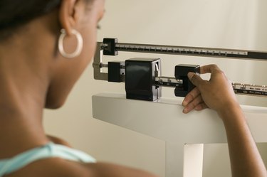 Woman Weighing Herself to determine her pounds of body fat