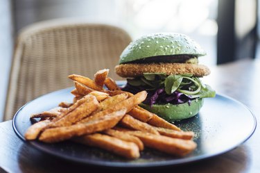 close-up of tofu burger on a green bun with sweet potato fries